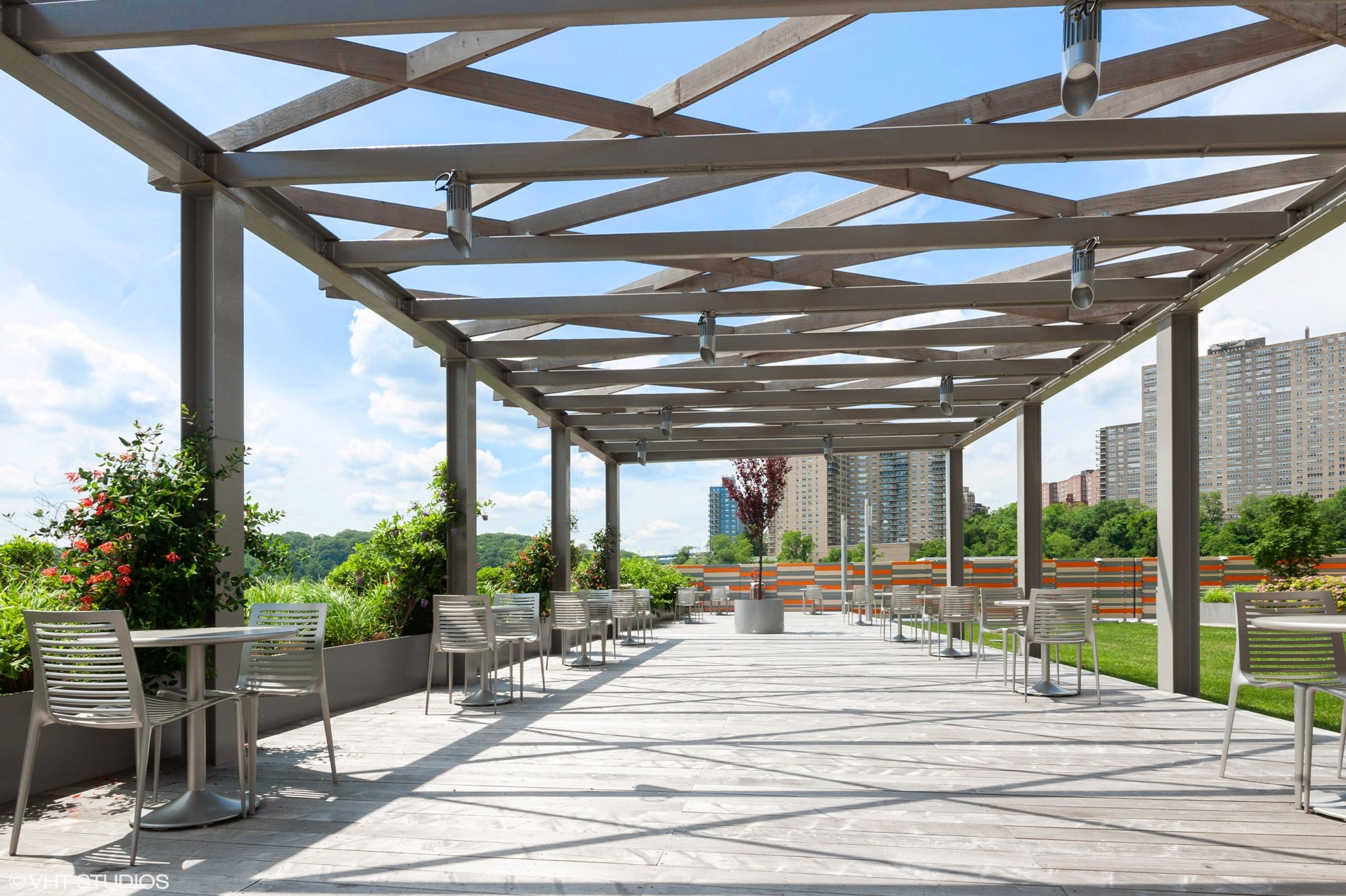 The Landscaped Garden Terrace at The Promenade, 150 west 225th street, is Furnished with modern tables & chairs under a pergola.